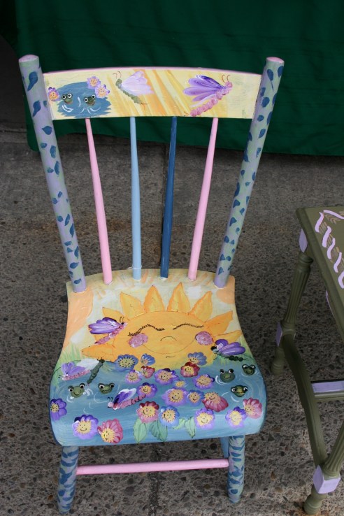 I want to like this.  I really do.  The happy face flowers have a strange appeal, and there is that whole Teletubbies sun thing going on.  But it would creep me out to sit on this chair, for sure.