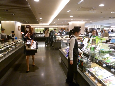 Isetan department store food halls. See the woman walking on the left? She is wearing a surgical face mask. About 10% of the people you see have one on, both in offices and out on the street. They are trying to prevent sickness, or in the case of someone who is already sick, they are protecting other people.